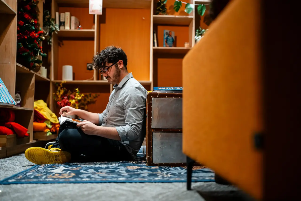A student sat on the floor reading a book.