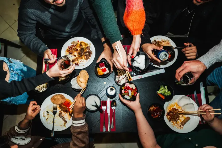 A birds eye view of a group of people enjoying a wide variety of delicious looking food.