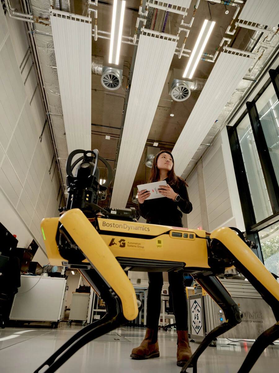 A student in a robotics lab holding a tablet