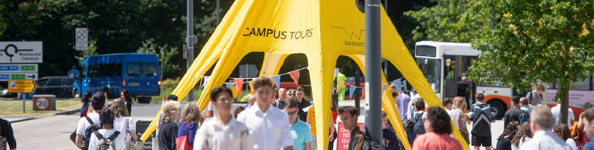 Prospective students visiting campus, a 'Campus Tour' yellow tent is featured