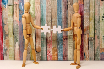 two wooden figures connecting puzzle pieces
