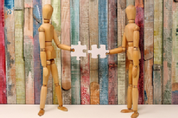 two wooden figures connecting puzzle pieces