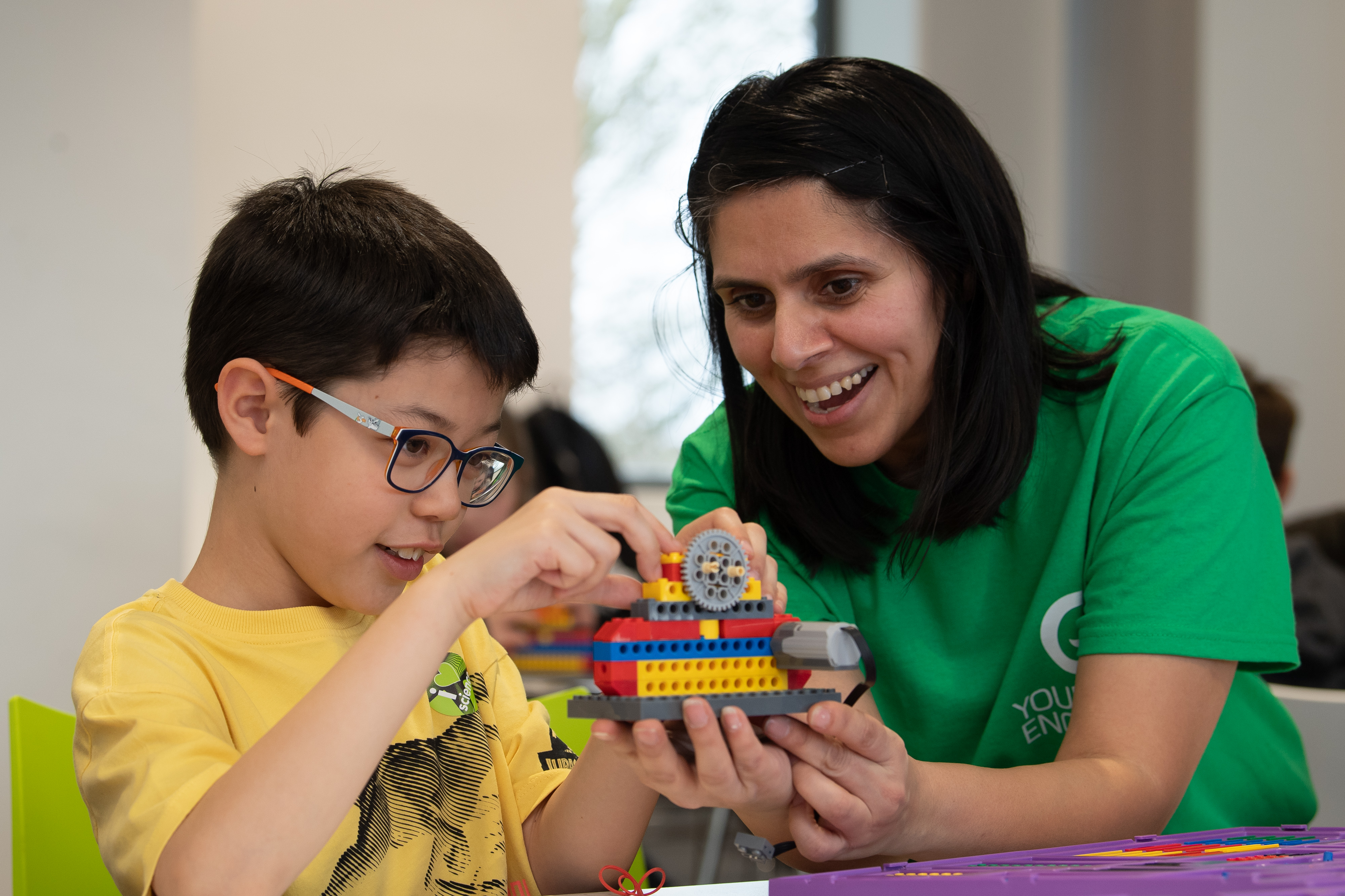 A boy and a woman smile as they build some lego