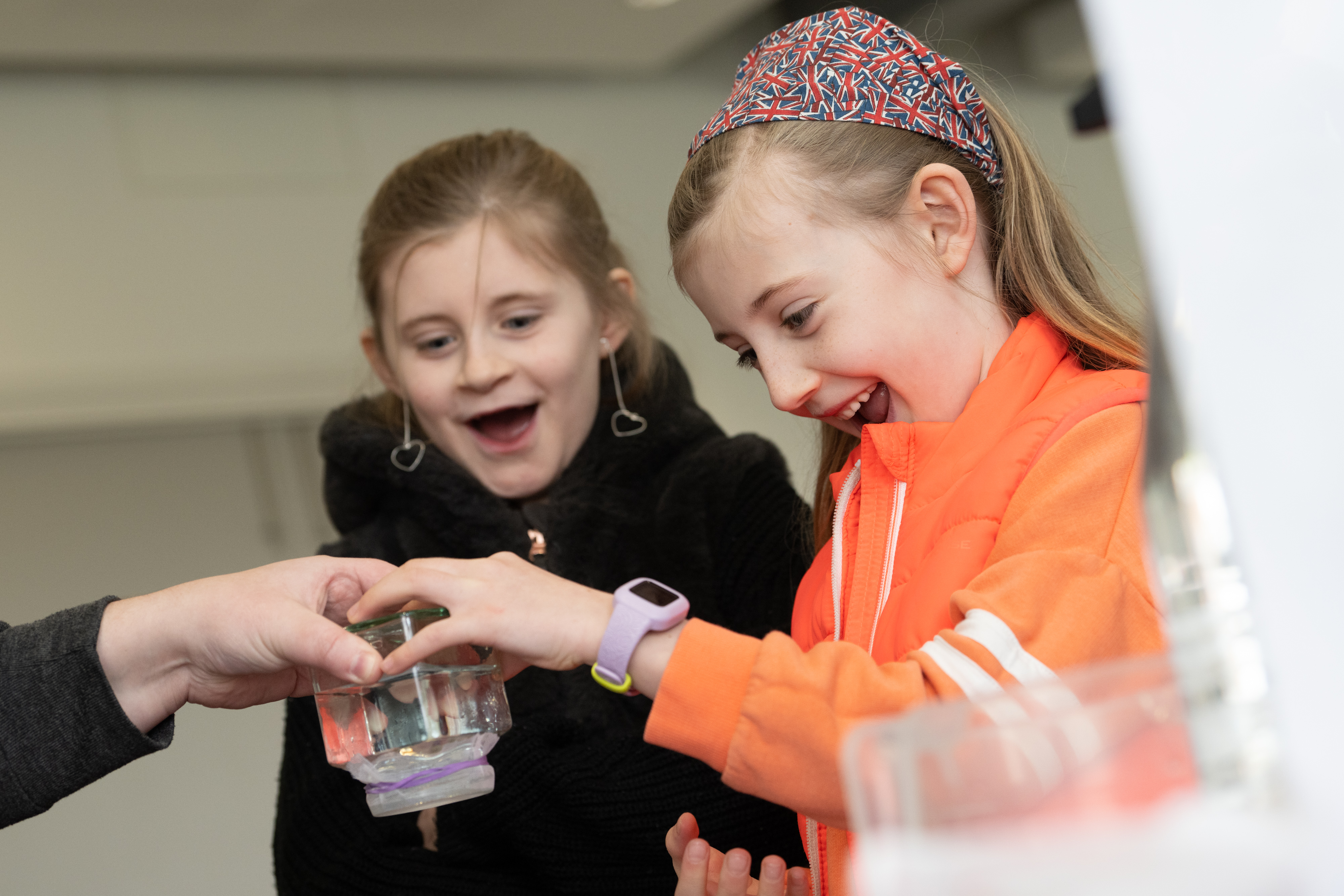 Two girls look excitedly at something in their hands. 