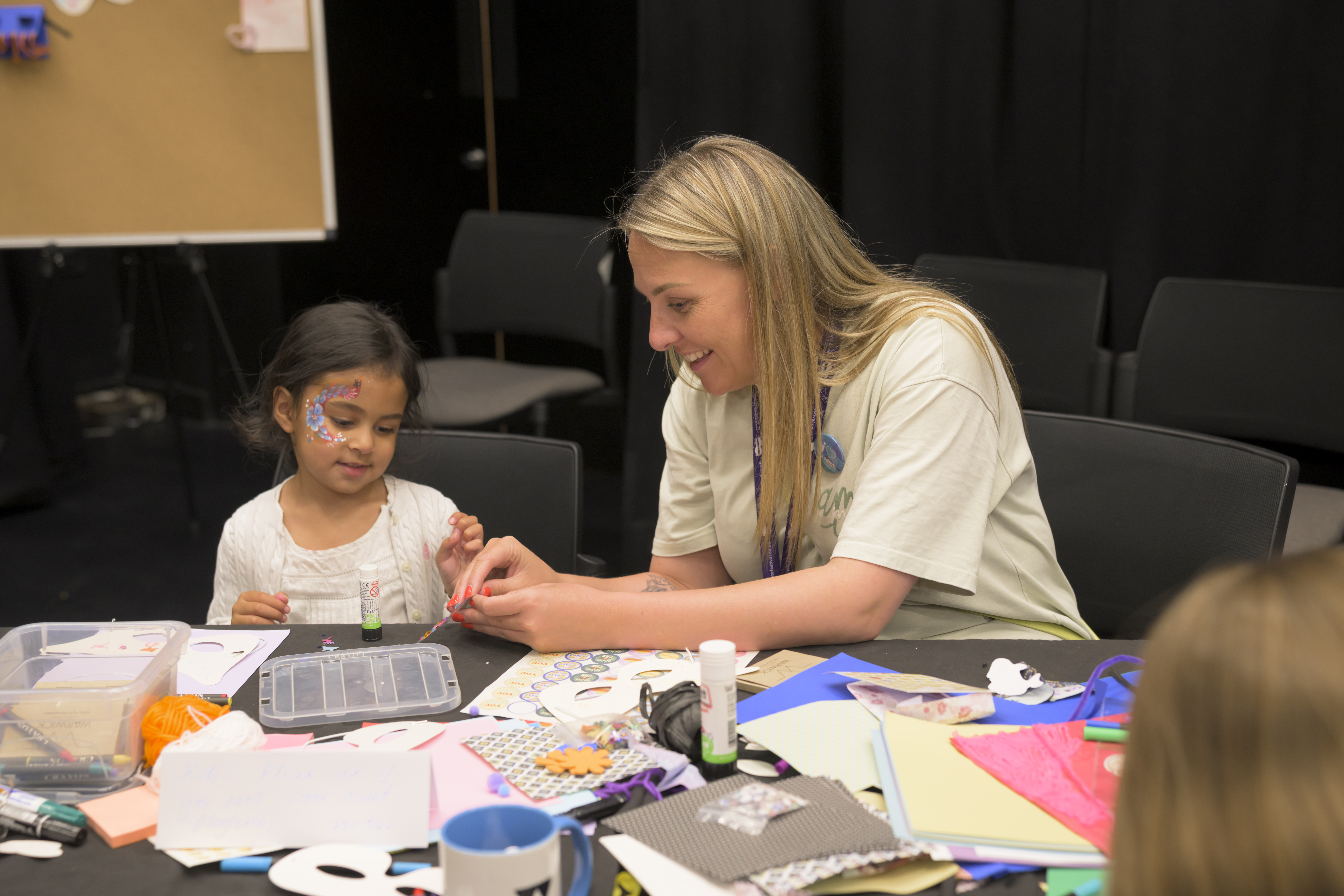 An adult helps a child with a craft activity
