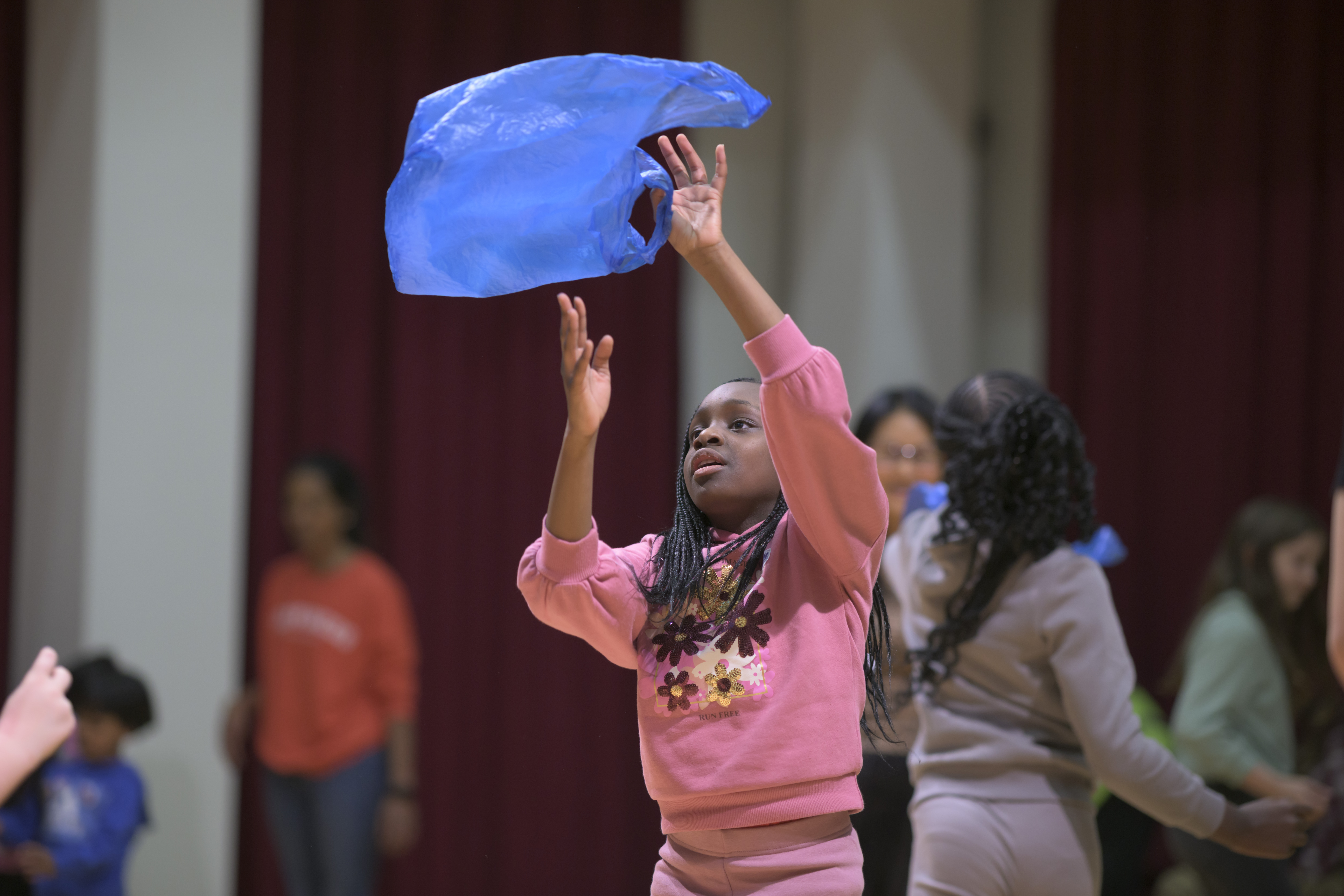 A child dances with a blue plastic bad during a workshop