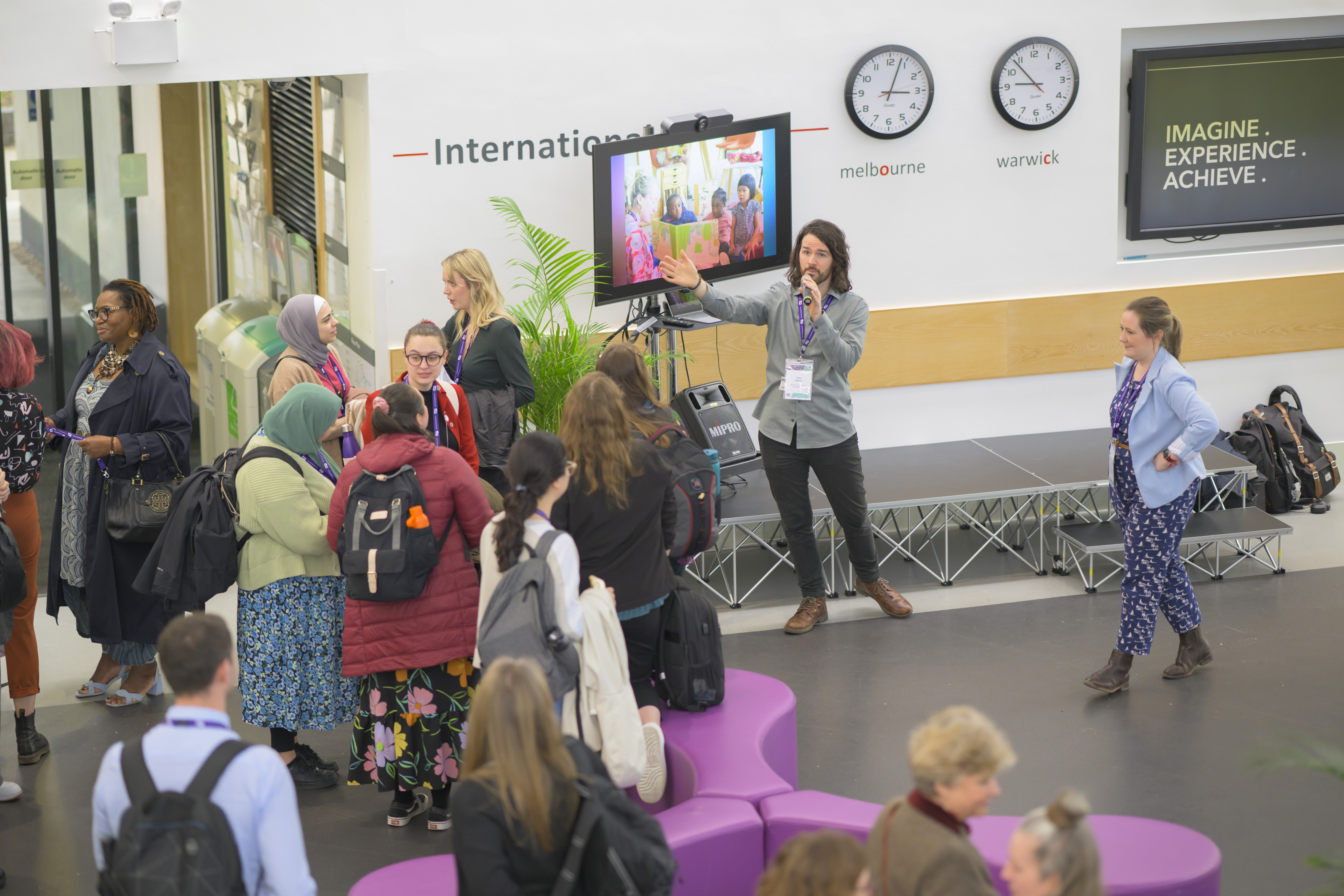 People gathered around a screen in the atrium