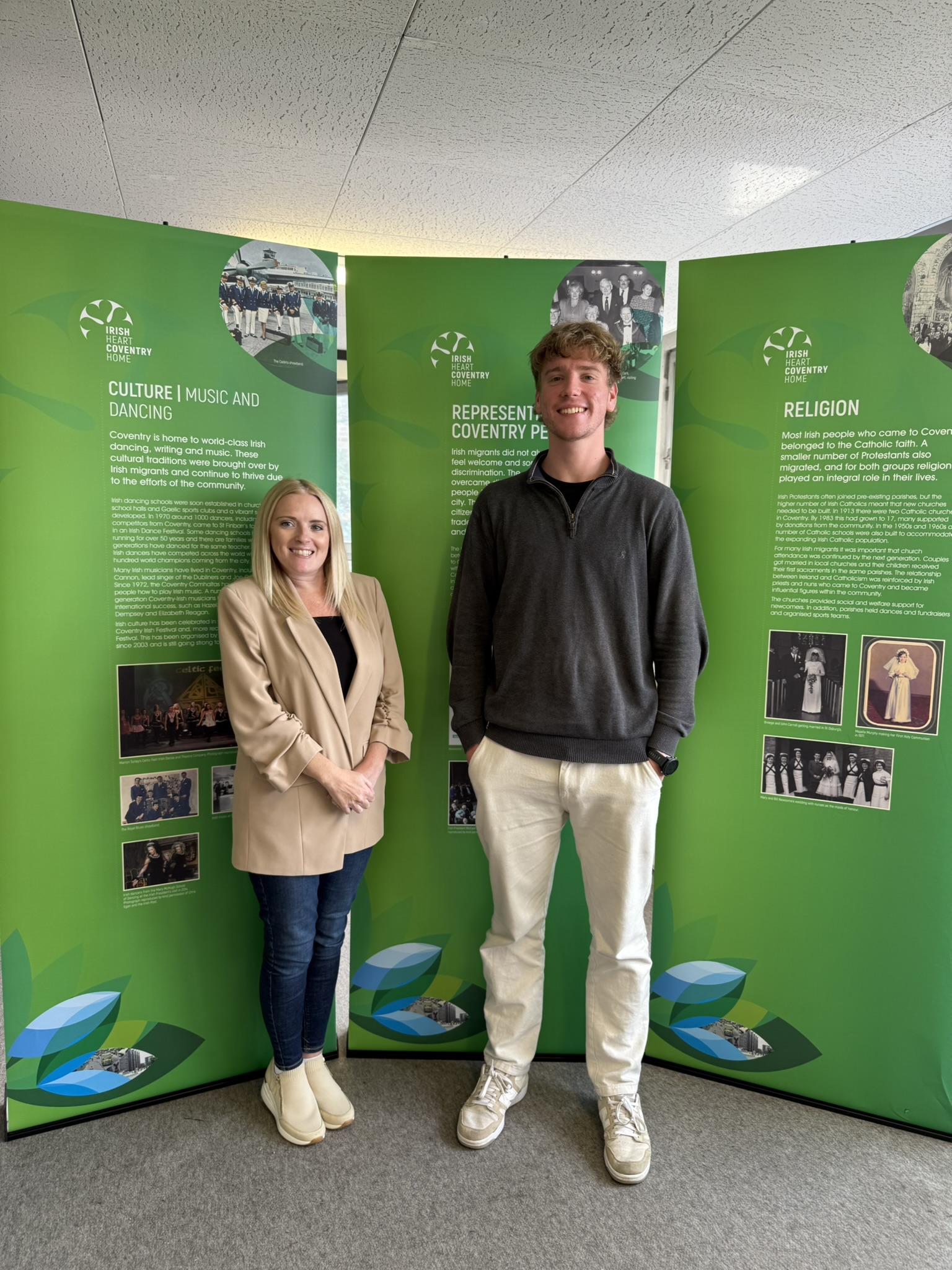 Caroline Brogan (left) and Charlie Byfield (right) stood against Coventry Irish Society posters