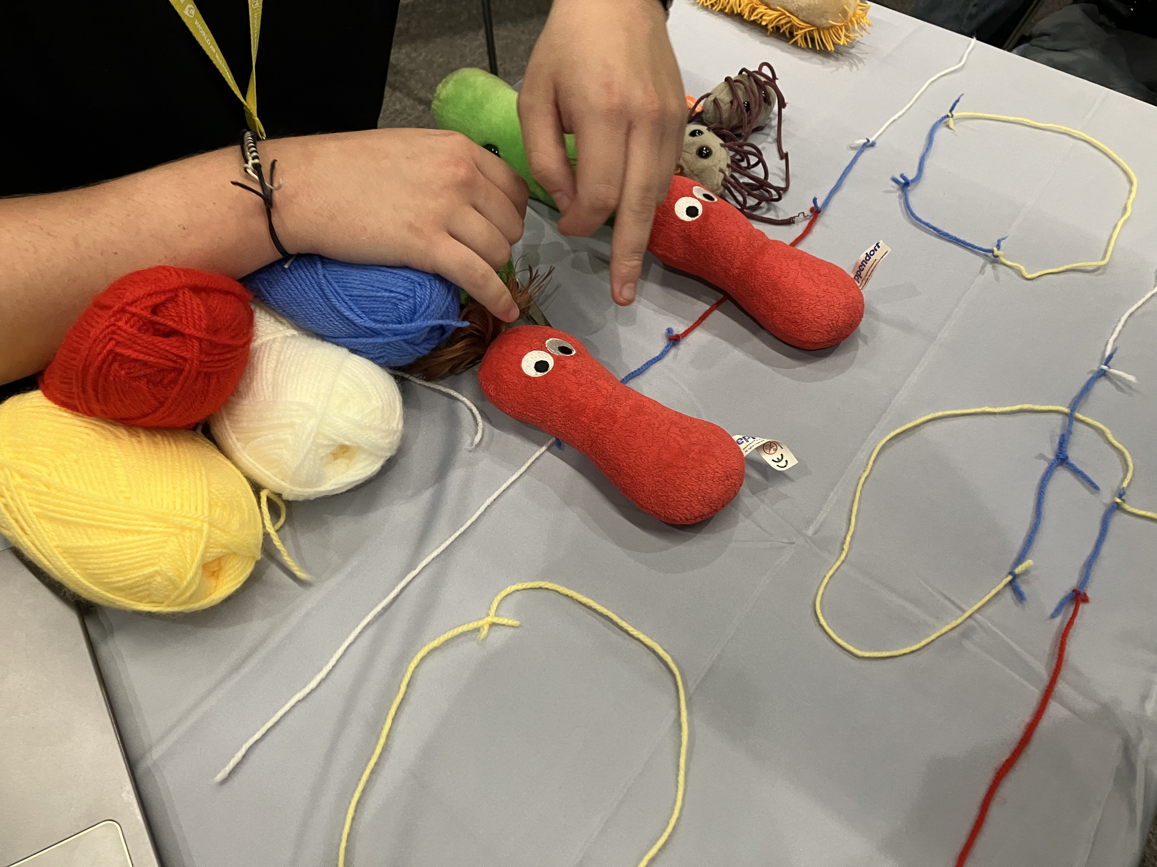 Some soft toys and balls of wool on a table. 