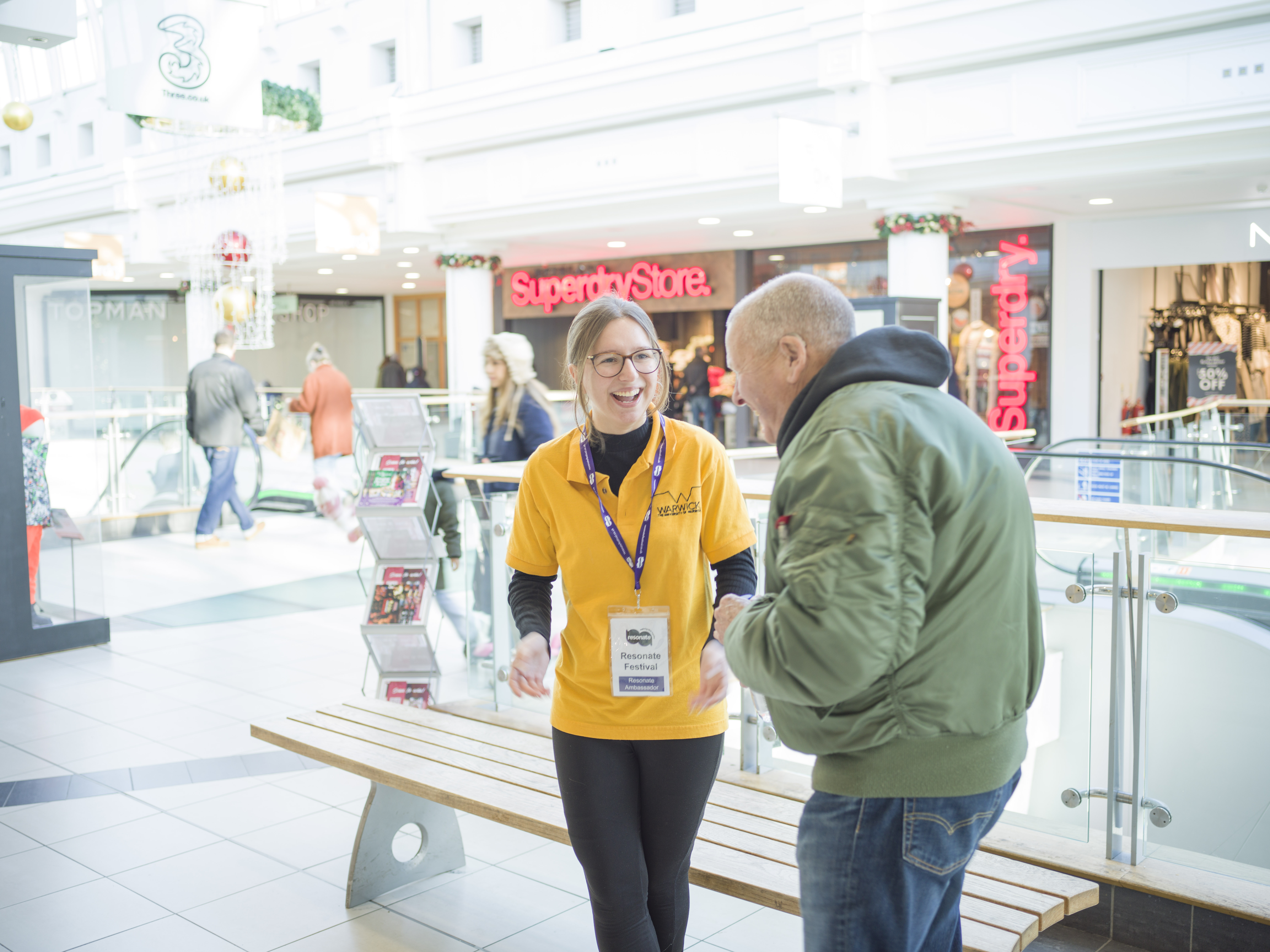 In the shopping centre, a student laughs with a member of the public. 