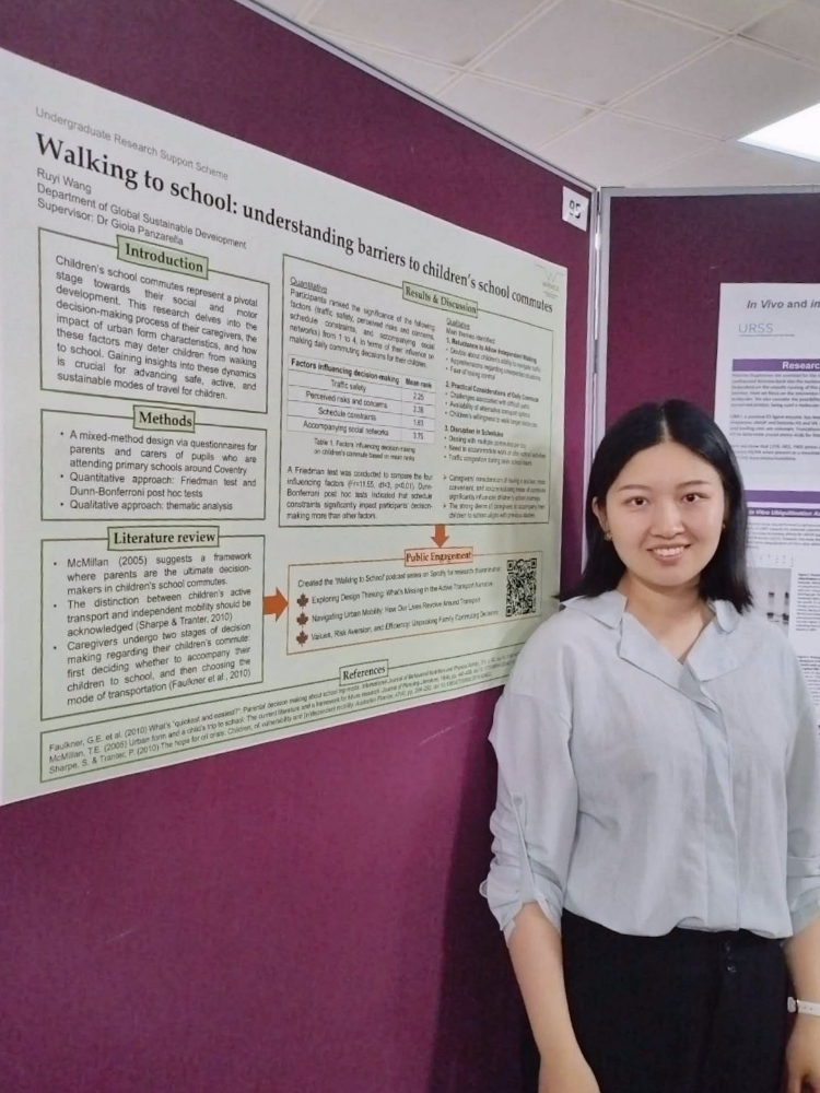 A photo of Ruyi standing next to a landscape academic poster with text on it. 