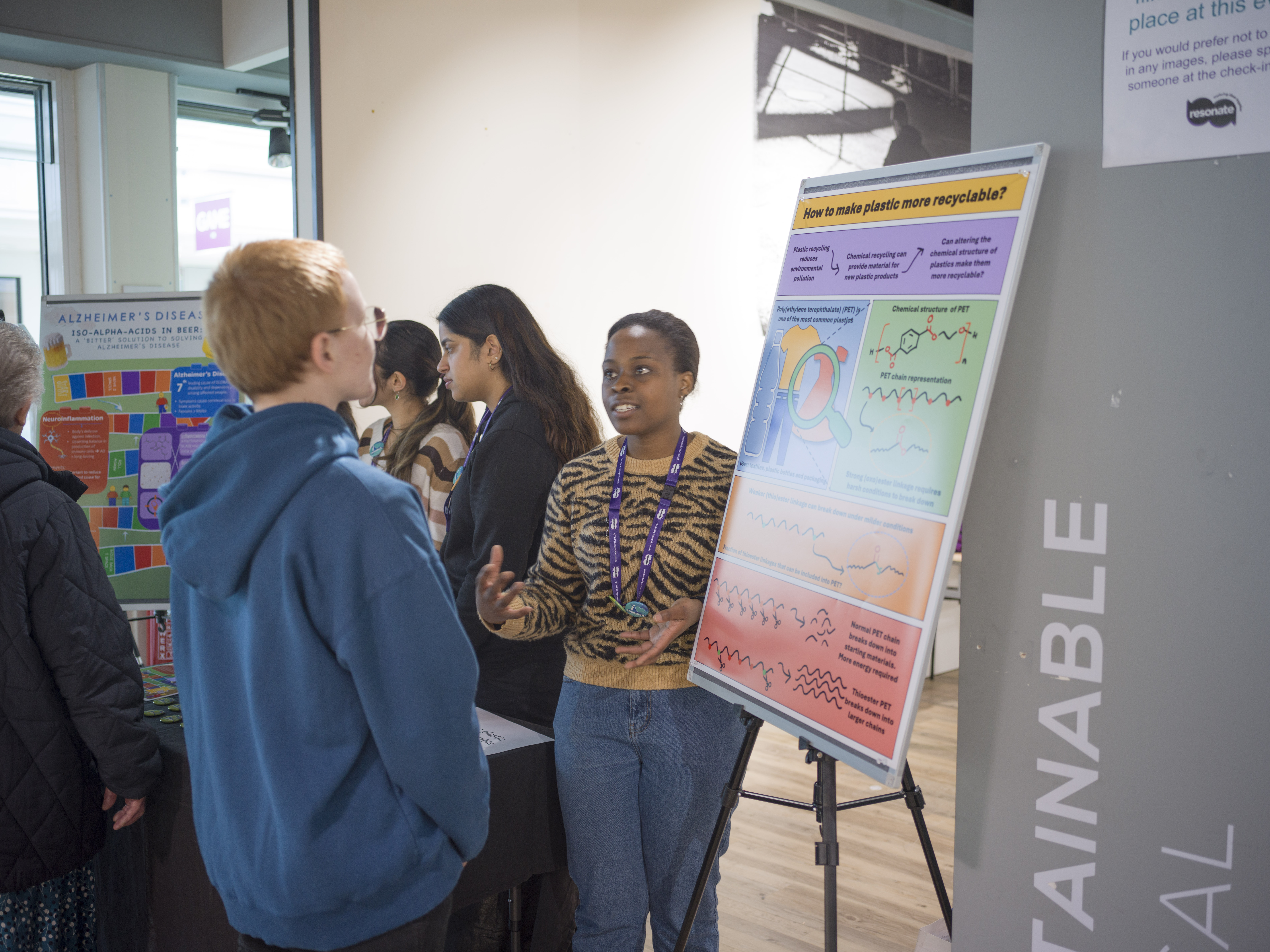 A student talks to a young person about their colourful poster. 