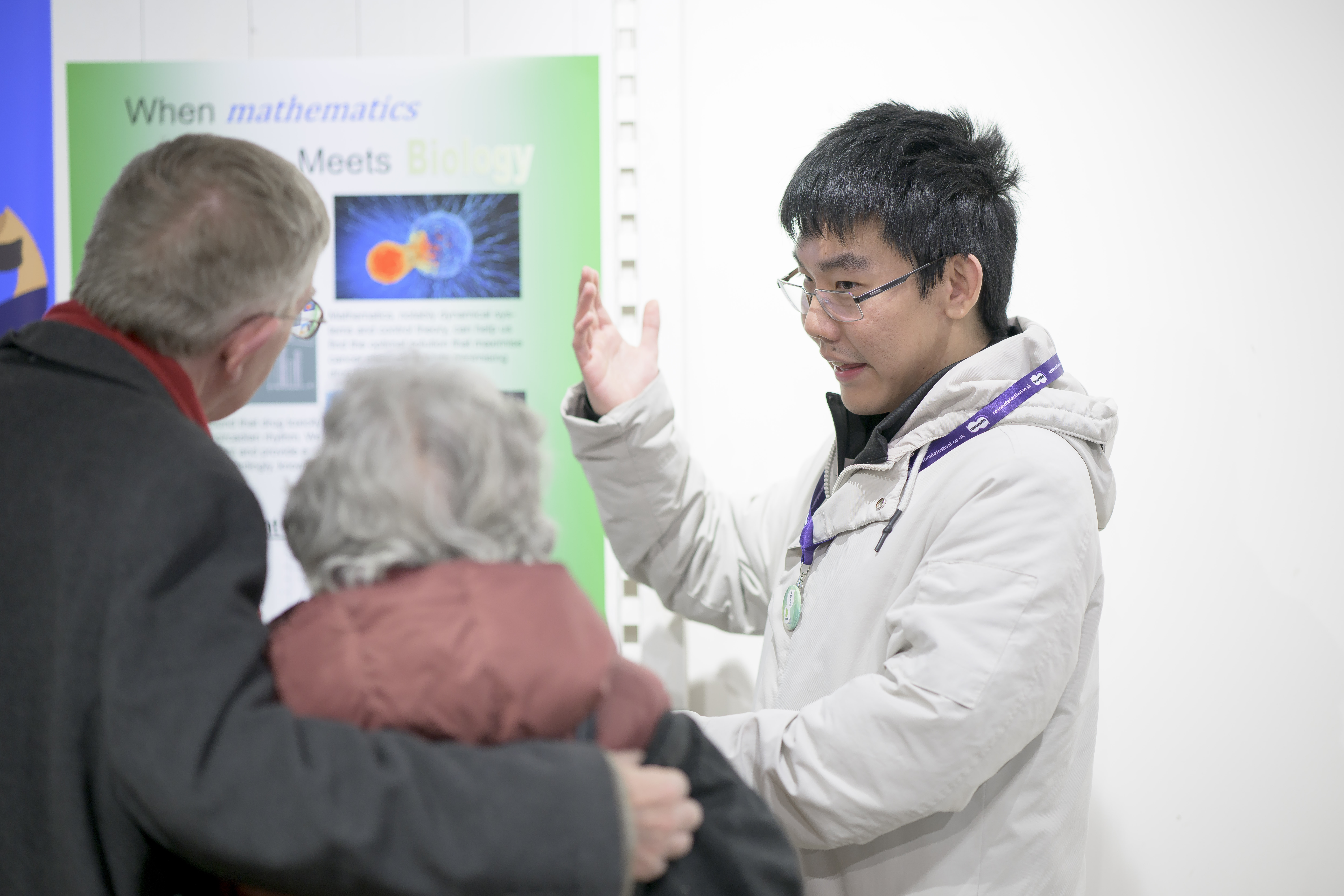 A student gestures while talking to two visitors. 