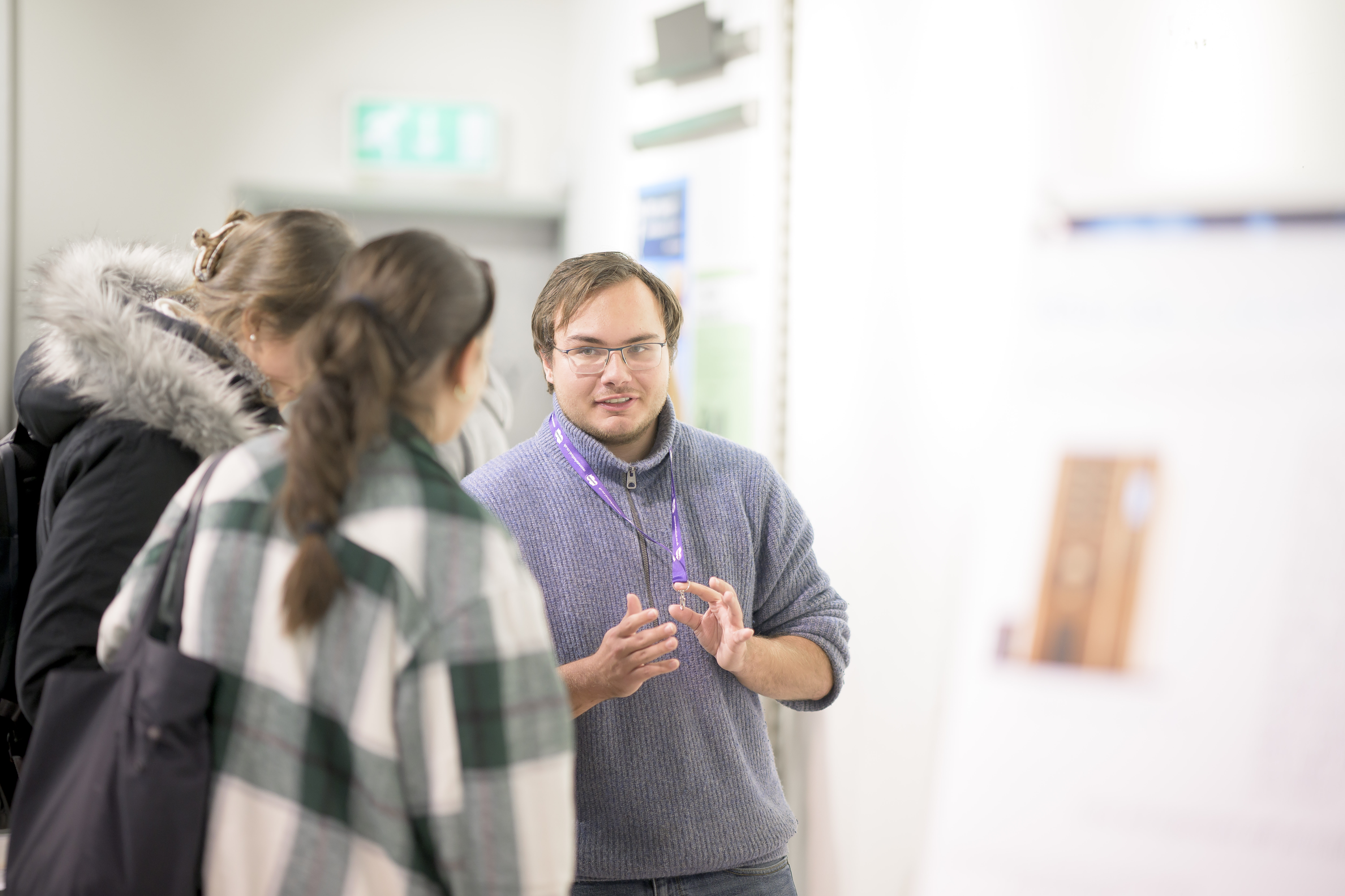 A student talks to two visitors by their poster. 