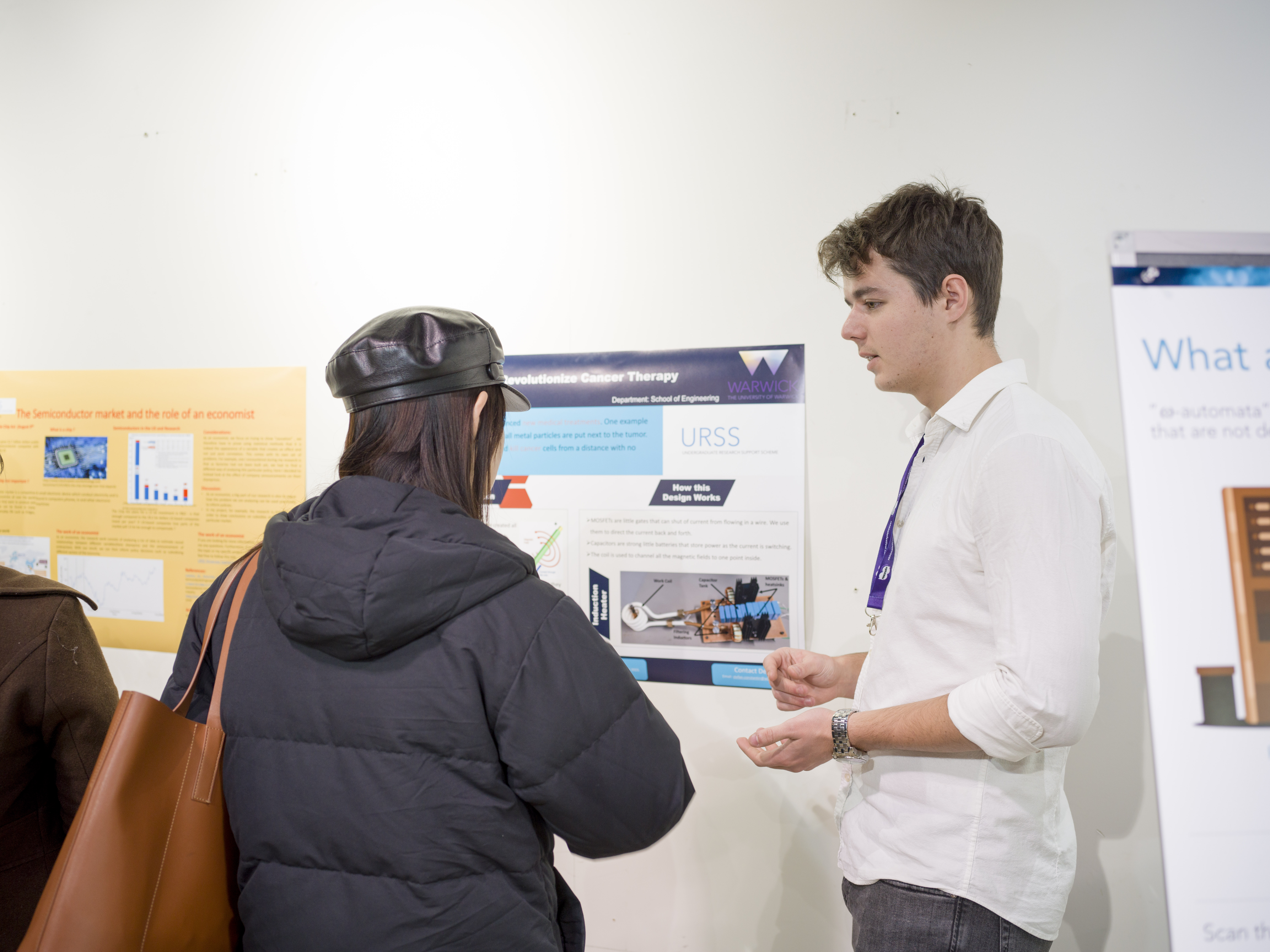 A student talks to a visitor about their poster. 
