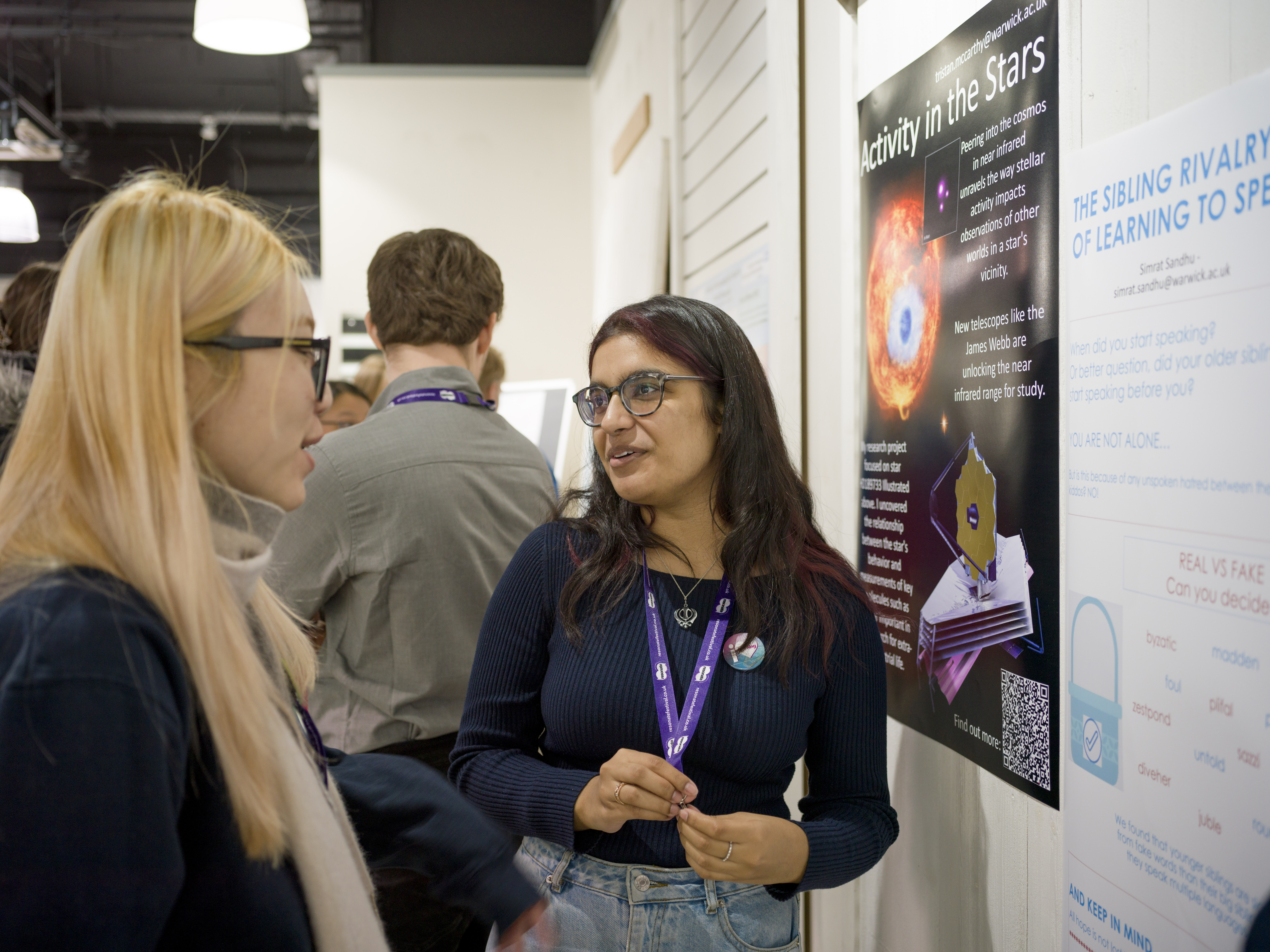 A student talking to a visitor next to their poster. 